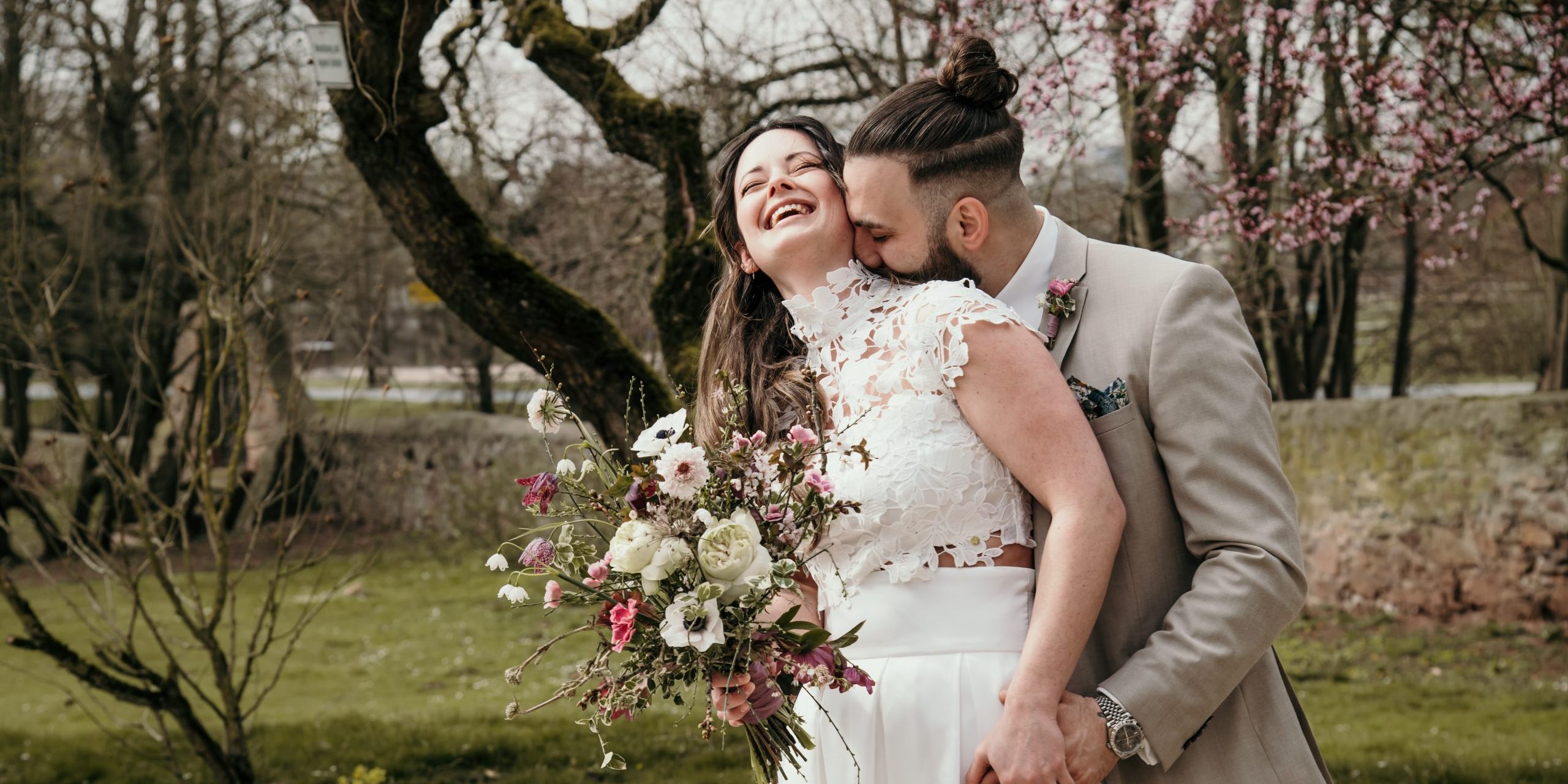 Bräutigam küsst Braut von hinten am Hals
