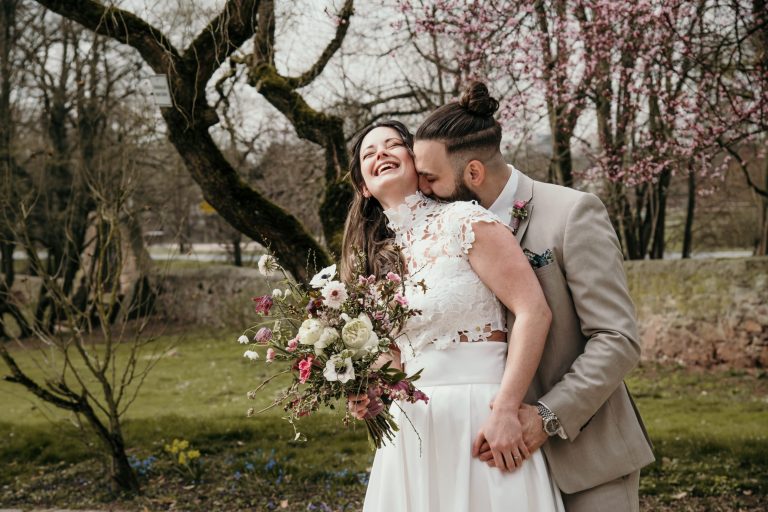 Bräutigam küsst Braut von hinten am Hals