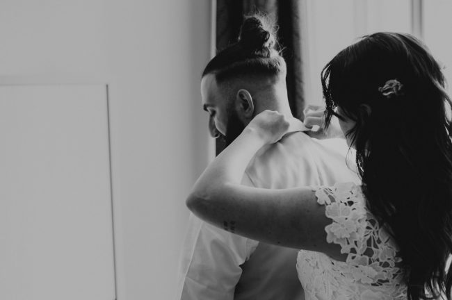 schwarz weiß, Braut klappt Bräutigam dem Hemdkragen um