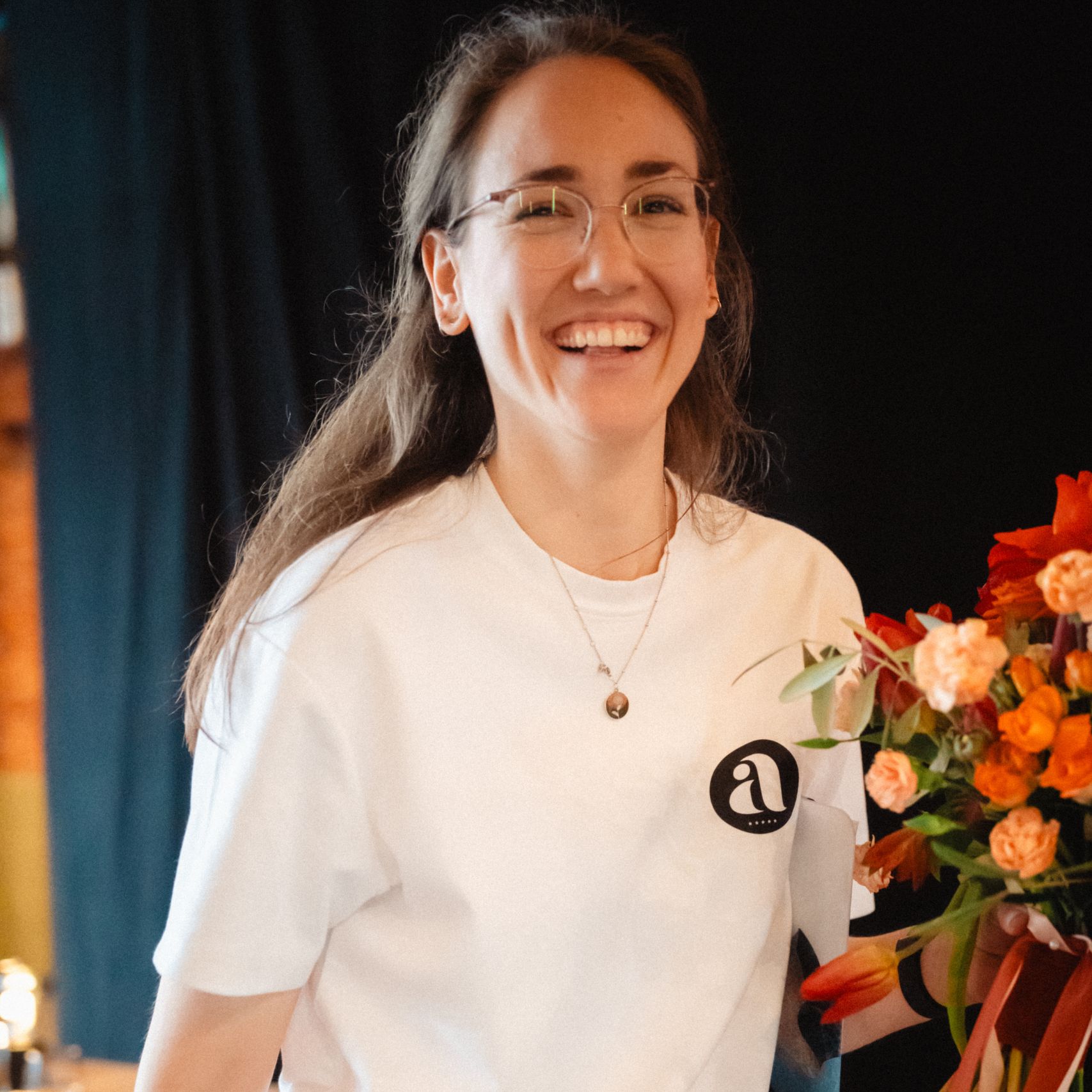 Alina geht lachend mit Brautstrauß und Klemmbrett unter dem Arm