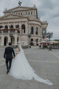 Brautpaar geht vor einem alten Gebäude von der Kamera weg