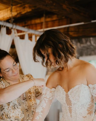 Brautatelier Herzlichkeit Anprobe Die Inhaberin vom Brautatelier Herzlichkeiten hilft einer frau bei der Kleideranprobe