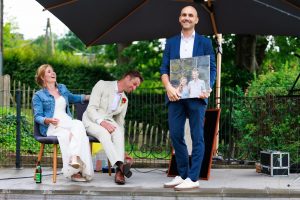 Andreas Fließgarten mit Foto im Vordergrund und lachendes Brautpaar im Hintergrund