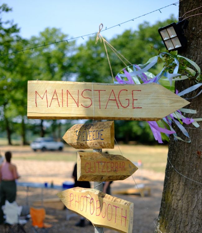 Wegweiser aus Holz auf dem Festival auf dem "Mainstage" steht